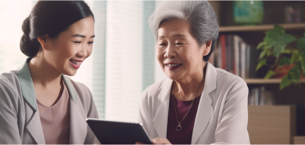 An elderly is smiling while holding an iPad with a young lady who is smiling beside her.
