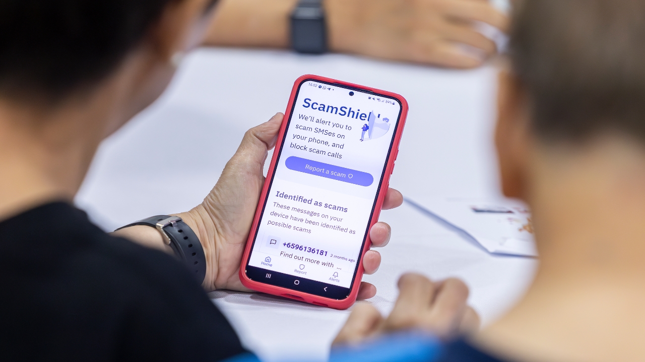 Community members looking and using the ScamShield app on their phone after installing