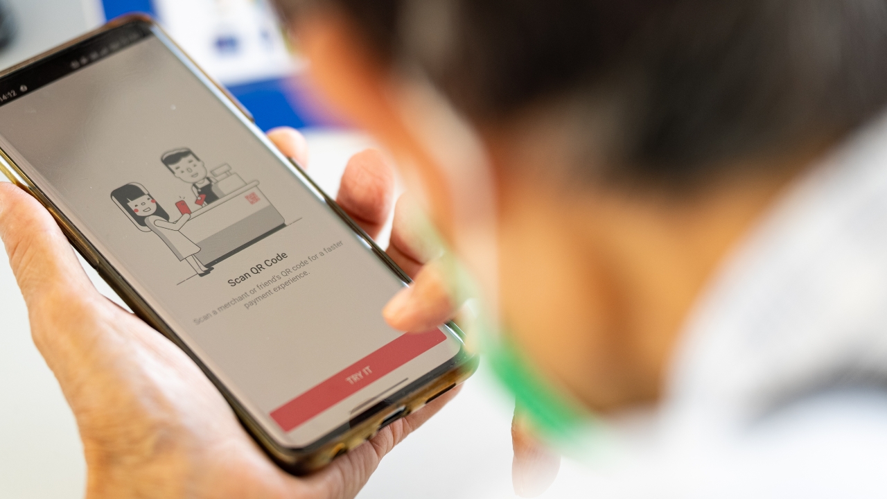 An elderly learning how to scan QR codes using the PayLah! app