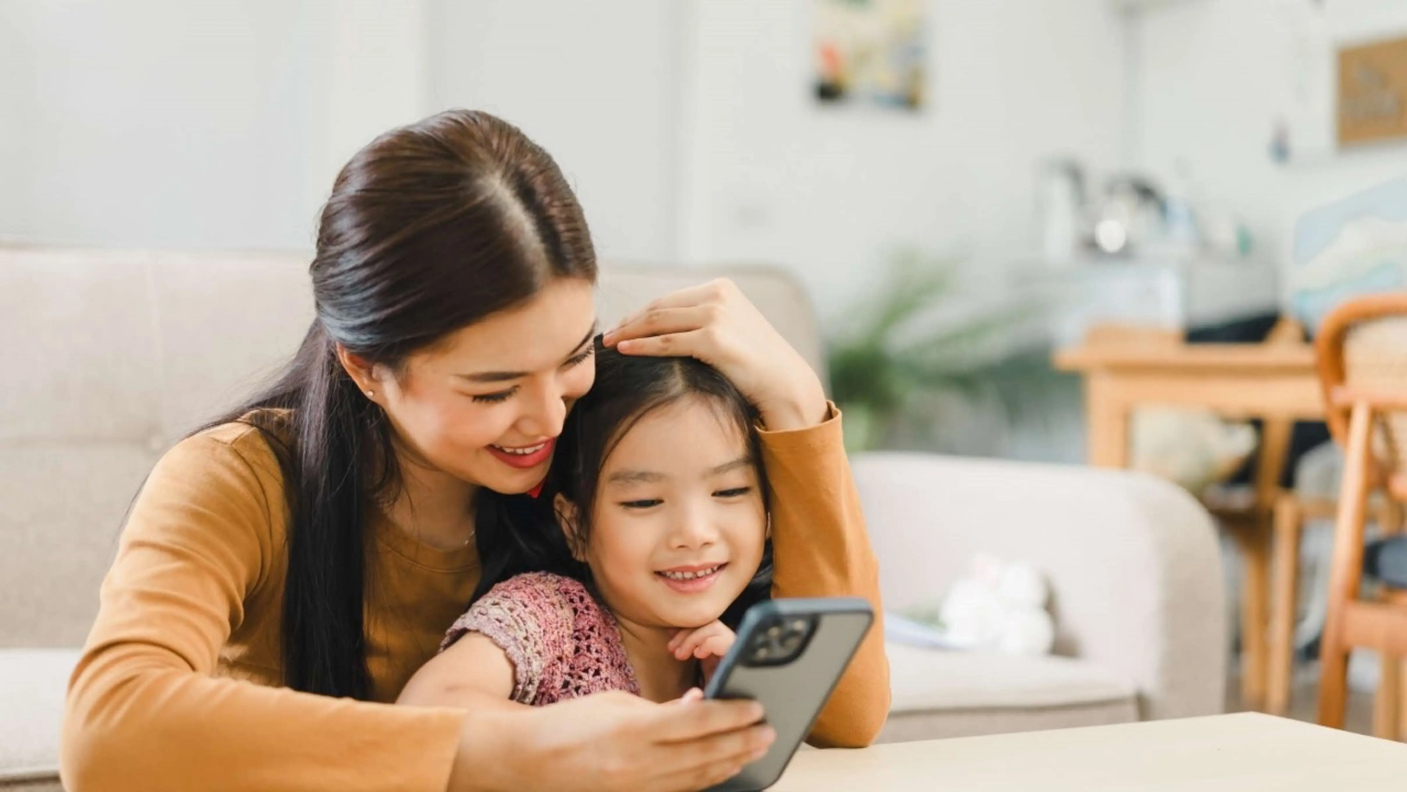 Mother and child sit together using phone.