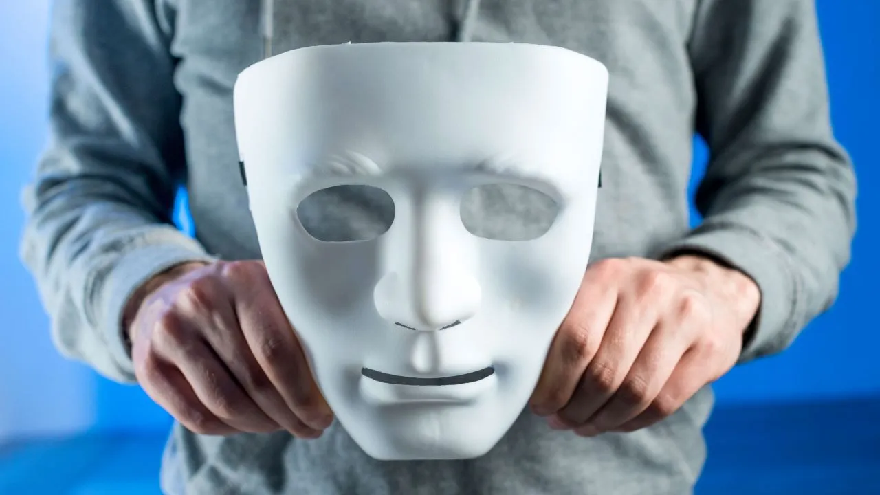 Person holding a plain white mask in front of their chest.