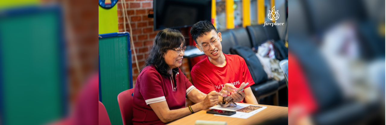 A youth volunteer guiding a senior in using a smartphone.