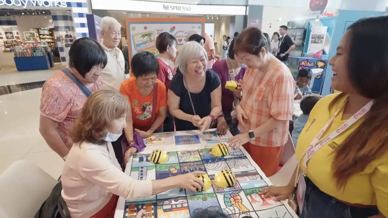 Seniors gathered around a table laughing and engaging with a BeeBots programing activity.