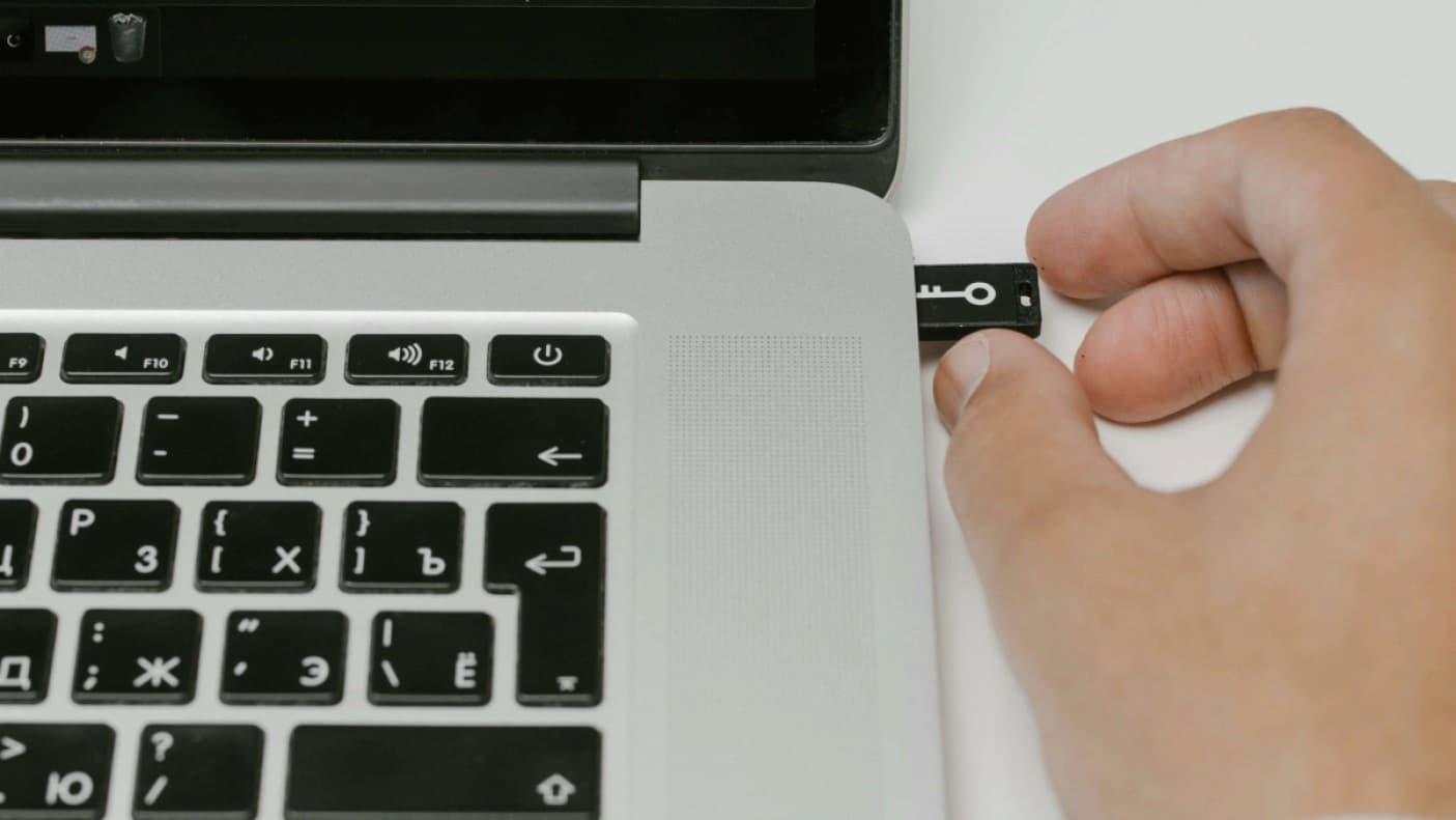 A person plugging in a device into a laptop.