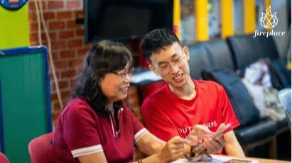 A youth volunteer guiding a senior in using a smartphone.